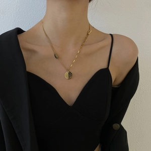 Détail du collier en acier titane doré avec chaîne asymétrique et pendentif pièce gravée