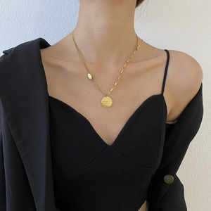 Détail d'un collier double épaisseur en titane doré avec pendentif rond gravé sur mannequin