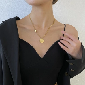 Détail d'un collier doré double épaisseur avec fermoir OT et pendentif sur un mannequin