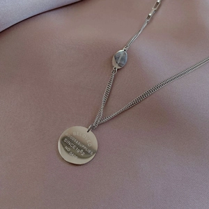 Vue macro du pendentif gravé et de la chaîne polie sur soie violette douce