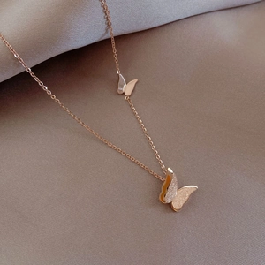 Detail of rose gold double butterfly necklace with textured wing and smooth finish
