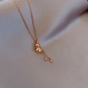 Detail of rose gold gourd pendant necklace with tassel chains on lavender silk fabric