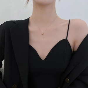 Close-up of golden gourd tassel necklace on female model wearing black suit