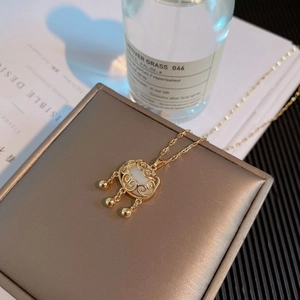 Gros plan du collier serrure Ruyi doré avec pierre blanche sur un coffret en soie