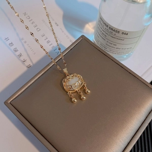 Détail du collier doré avec pendentif serrure porte-bonheur, opale et trois clochettes