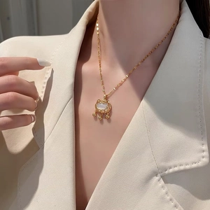 Détail d'un collier pendentif chat doré avec opale et perles dorées sur un mannequin