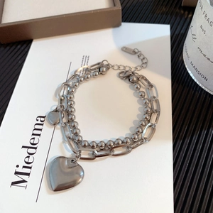 Detail of silver titanium steel layered bracelet featuring heart pendants and beaded chain