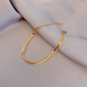 Detail of golden double-layer titanium steel bracelet with snake chain and bead design