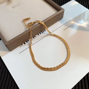 Detail of gold double-layer bracelet with sleek snake chain and cylinder beads