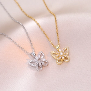 Detail of gold and silver butterfly pendants with sparkling cubic zirconia on pink silk