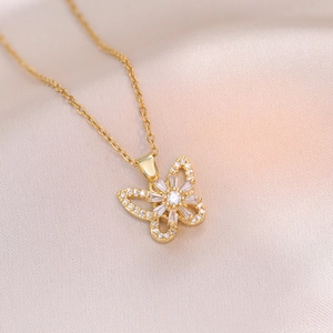 Close-up of golden butterfly necklace with shimmering zircon inlay on pink satin fabric