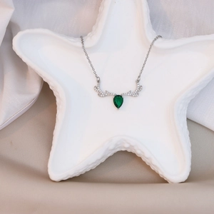 Macro shot of silver deer antler necklace with a green teardrop-shaped gemstone inlay