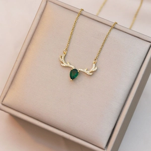 Macro view of deer antler necklace with pear-cut emerald stone and zircon pavé detailing