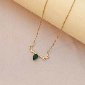 Detailed close-up of deer antler necklace with green teardrop zircon on silk fabric