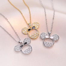 Detail of Mickey-shaped pendants with zircon pavé and black bow on satin fabric
