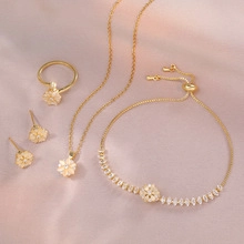 Elegant gold flower jewelry set with sparkling zircon on premium pink silk background