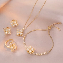 Macro detail of a gold-plated four-leaf clover jewelry set on a pink silk background