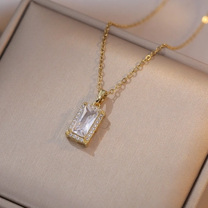 Gros plan d'un collier doré avec pendentif rectangulaire en zircon sur boîte à bijoux