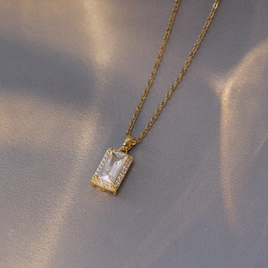 Détail d'un collier doré avec pendentif rectangulaire en zircon sur tissu en soie