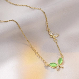 Close-up of gold butterfly necklace with olive green cat-eye stone and zircons on silk