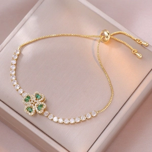 Adjustable gold bracelet featuring a rotating clover pendant with green and clear zircon