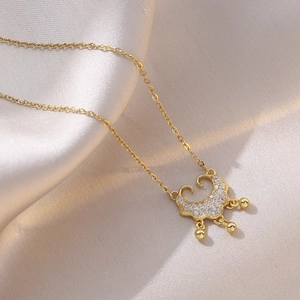 Golden Ruyi lock necklace with pavé cubic zirconia and hanging beads on silk background