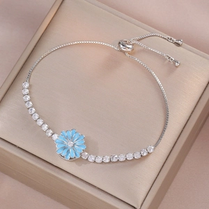 Adjustable silver bracelet with sparkling zircon stones and a blue daisy charm pendant