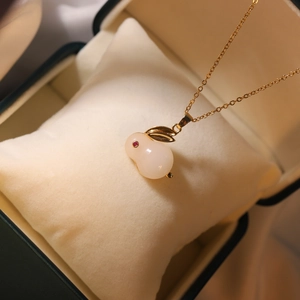 Detailed macro shot of a jade rabbit pendant with zircon eyes on a golden necklace
