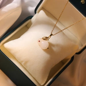 Detailed view of a gold rabbit pendant with a white stone and red zircon eye in a gift box