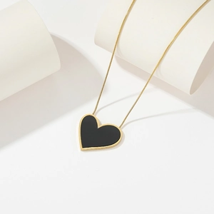 Close-up of gold snake chain with black heart pendant on a modern display