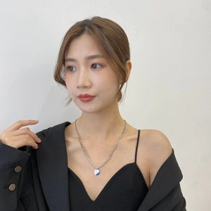 Détail d'un collier en titane argenté avec chaîne plate et pendentif disque sur un mannequin