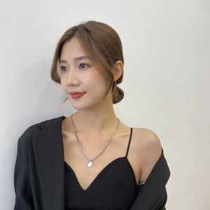 Vue rapprochée d'un collier en argent avec pendentif rond porté par un mannequin