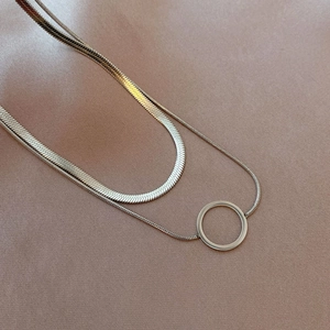 Detail of layered gold titanium necklace featuring a snake chain and round open pendant