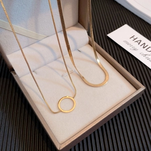 Detail of layered gold titanium snake chain and minimalist circle pendant necklace