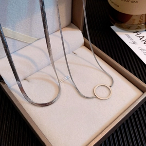 Detail view of silver titanium double-layer snake chain necklace in a beige jewelry box