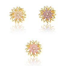 Detailed macro view of three floral zircon earrings in gold, pink, and purple colors