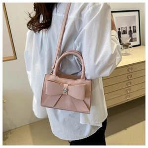 Sac à main rose avec nœud et cristal en cœur porté à l'épaule dans un décor intérieur