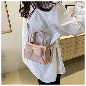 Détail du sac à main rose avec nœud et cristal en forme de cœur sur une bandoulière