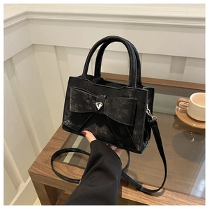 Détail du sac à main noir avec nœud papillon, cristal en cœur et cuir synthétique mat