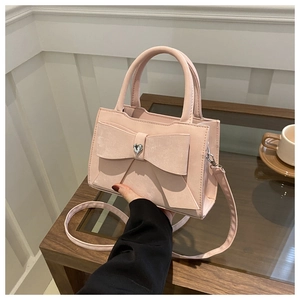 Détail du sac rose à nœud avec cristal en cœur sur une table de café élégante
