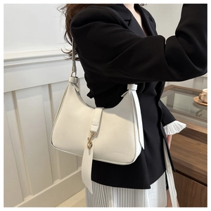 Detail of white leather hobo bag featuring a gold metal hook closure and long decorative strap
