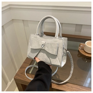 Détail du sac argenté avec nœud papillon, strass en cœur et texture mate élégante