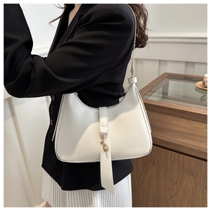 Close-up of a white hobo bag with a gold metal clasp and matte leather texture