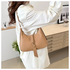 Detail of hobo shoulder bag featuring a gold metal buckle and smooth leather texture