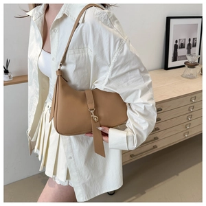 Detail of caramel leather crescent underarm bag with gold lock and vertical strap