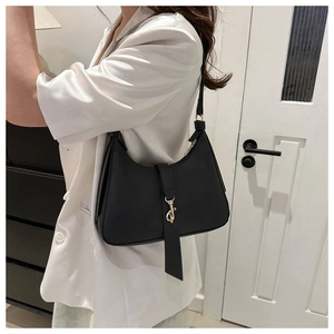 Detailed view of black matte leather hobo bag with gold buckle on white satin suit