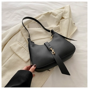 Chic black hobo underarm bag with gold metal clasp on a stylish cream blazer backdrop