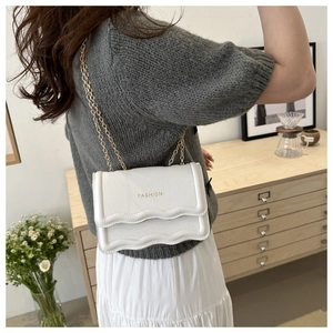 Detailed view of white chain bag with wave-edge flap and embossed FASHION text