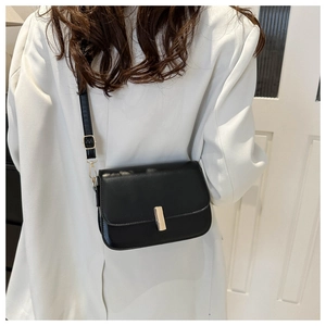 Minimalist black crossbody flap bag with gold metal buckle and adjustable strap