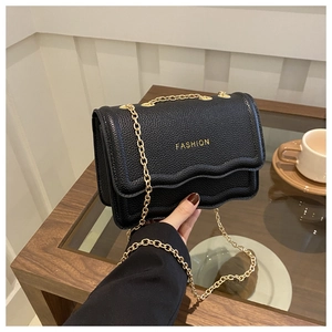 Detail of black pebbled leather chain bag with scalloped flap and gold Fashion text
